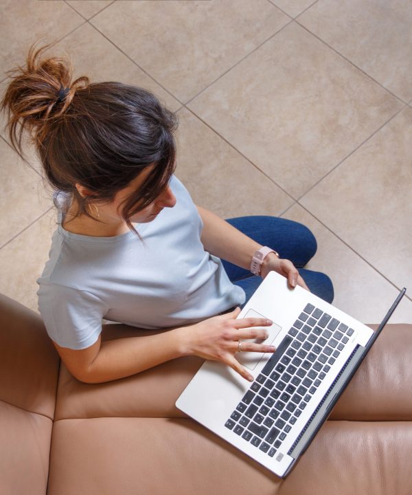Young women  working with laptop while sitting on the floor at home top view